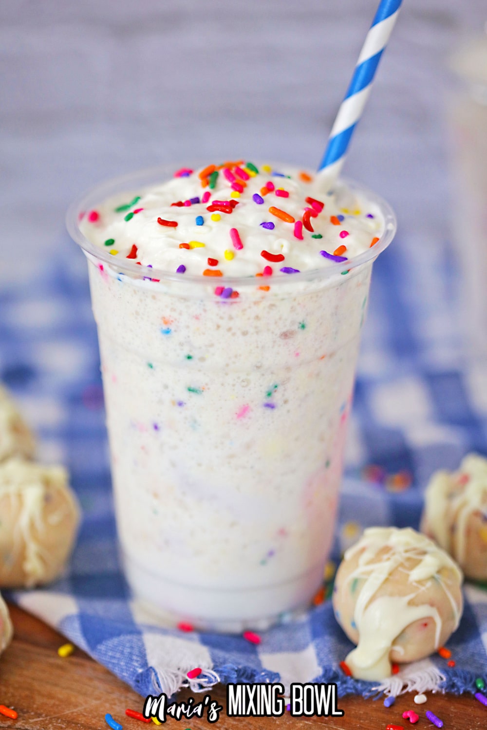 birthday cake Frappuccino on a blue and white checkered towel with a blue and white striped straw