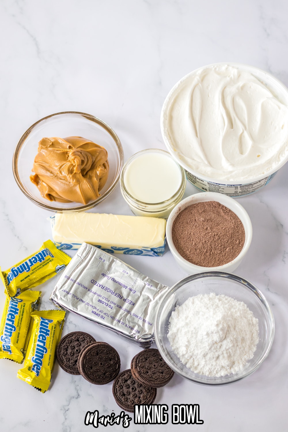 peanut butter, whipped topping, milk, chocolate pudding mix, oreo cookies, butterfinger bars, cream cheese and powdered sugar on a white marble background