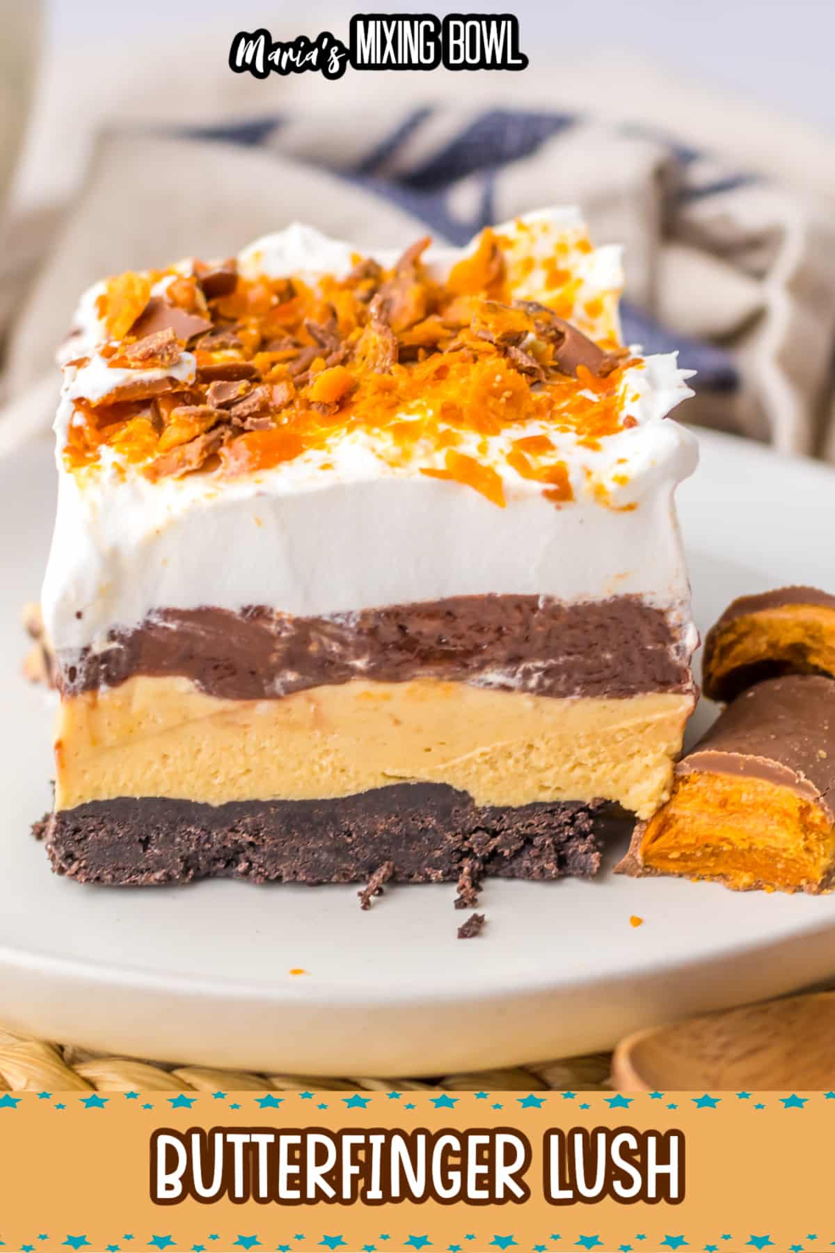 slice of butterfinger lush on a white plate with two butterfinger bars beside it.