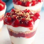 close up of a cherry cheesecake cup on a white marble background