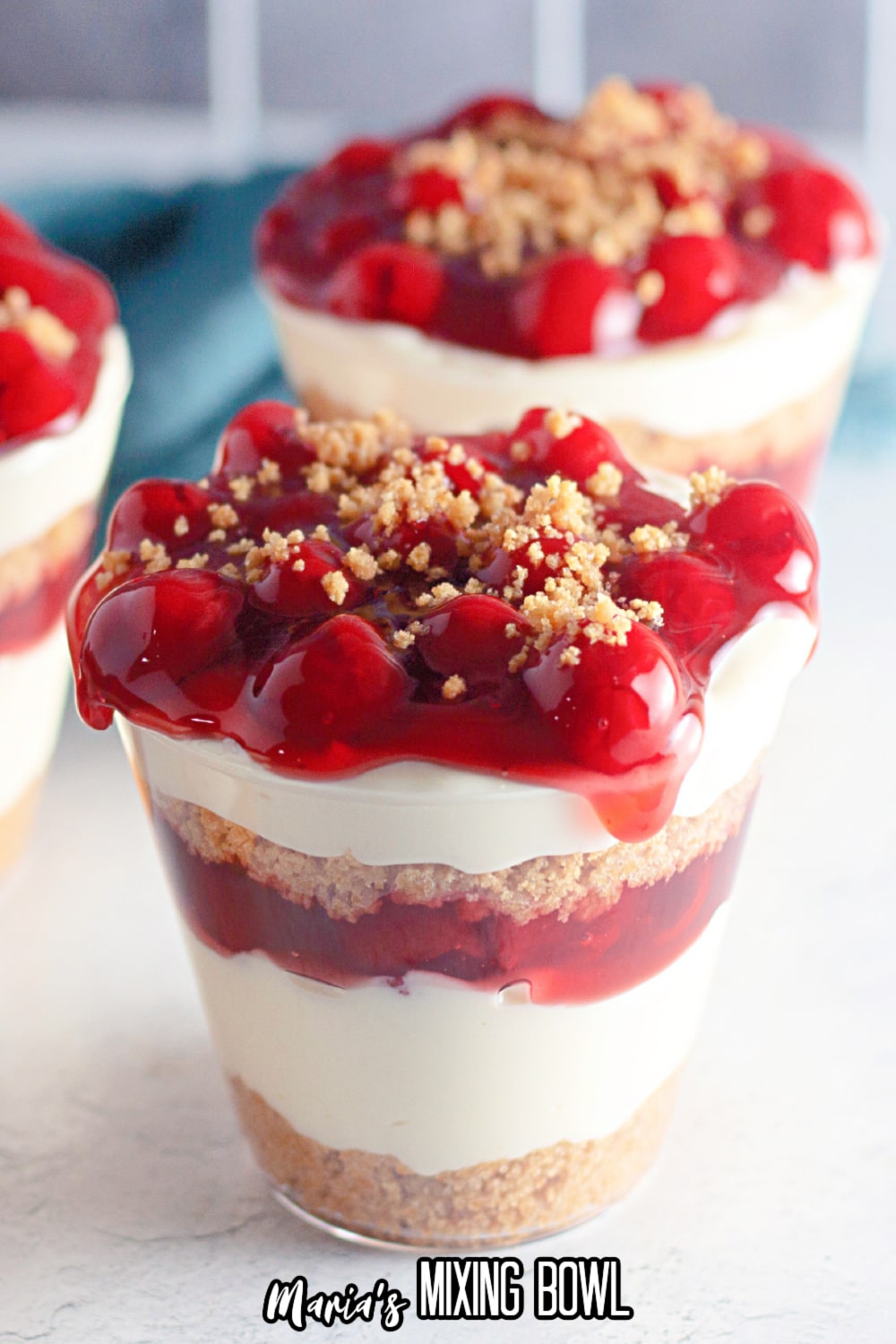 close up of a cherry cheesecake cup on a white marble background
