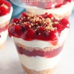 close up of a cherry cheesecake cup on a white marble background