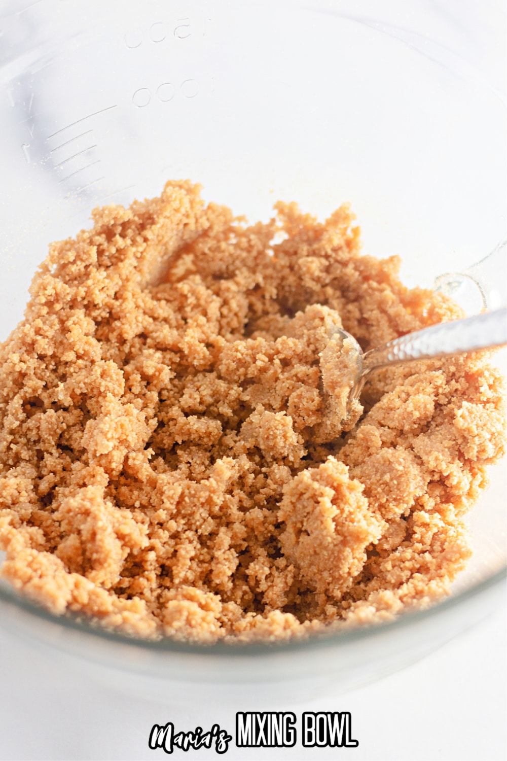 graham cracker crust in a small mixing bowl being mixed with a fork