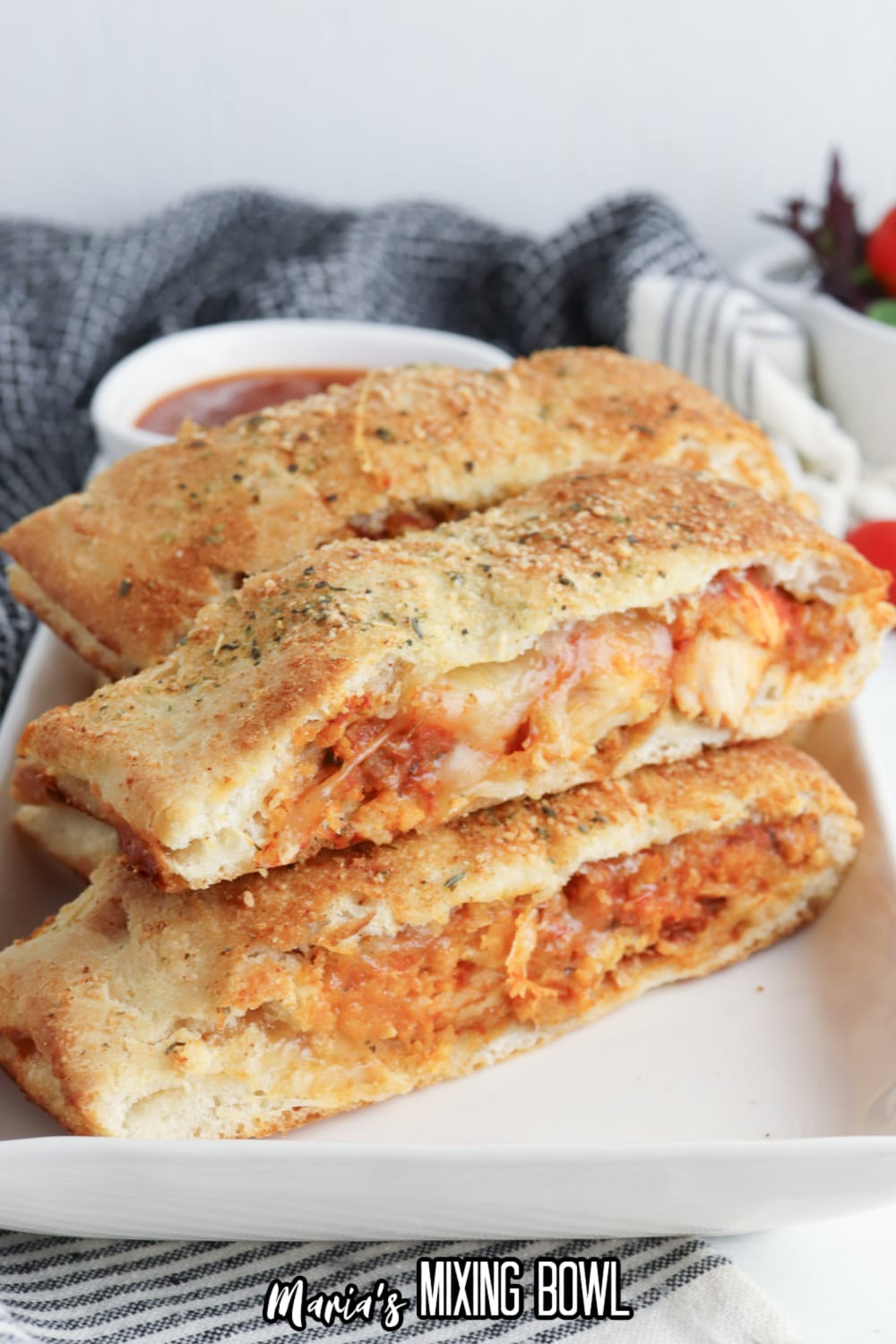 slices of stromboli on a white rectangular platter with a jar of pasta sauce