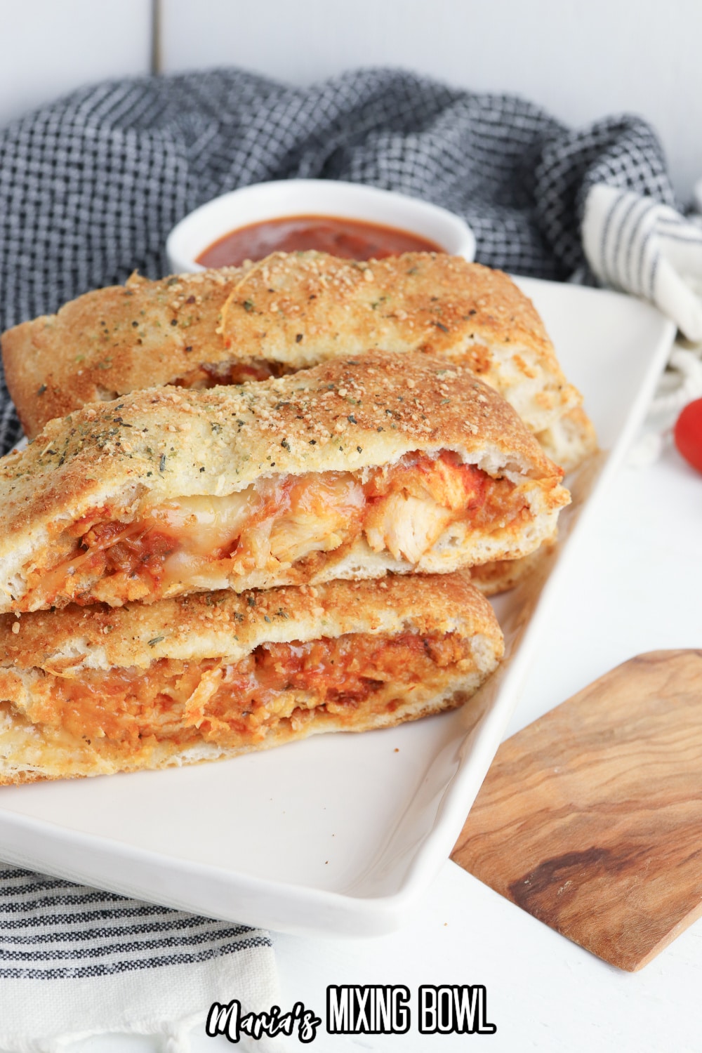 slices of stromboli on a white rectangular platter with a jar of pasta sauce