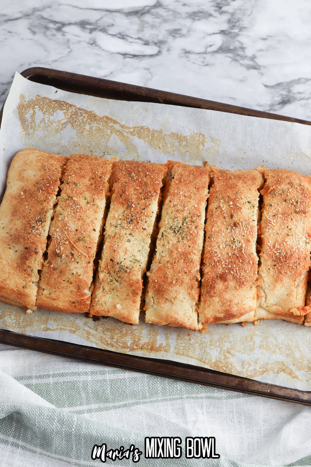 baked stromboli cut into slices in on a parchment lined baking sheet