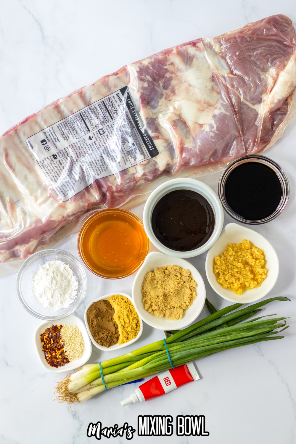 slab of ribs, soy sauce, seasonings, vinegar, cornstarch, green onions and red food coloring on a white background