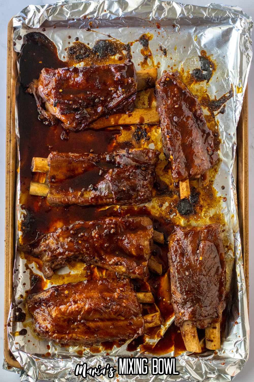 ribs laid out on a parchment lined baking sheet to go in the broiler