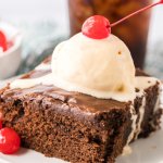 slice of double fudge coca cola cake on a small white plate topped with a scoop of ice cream