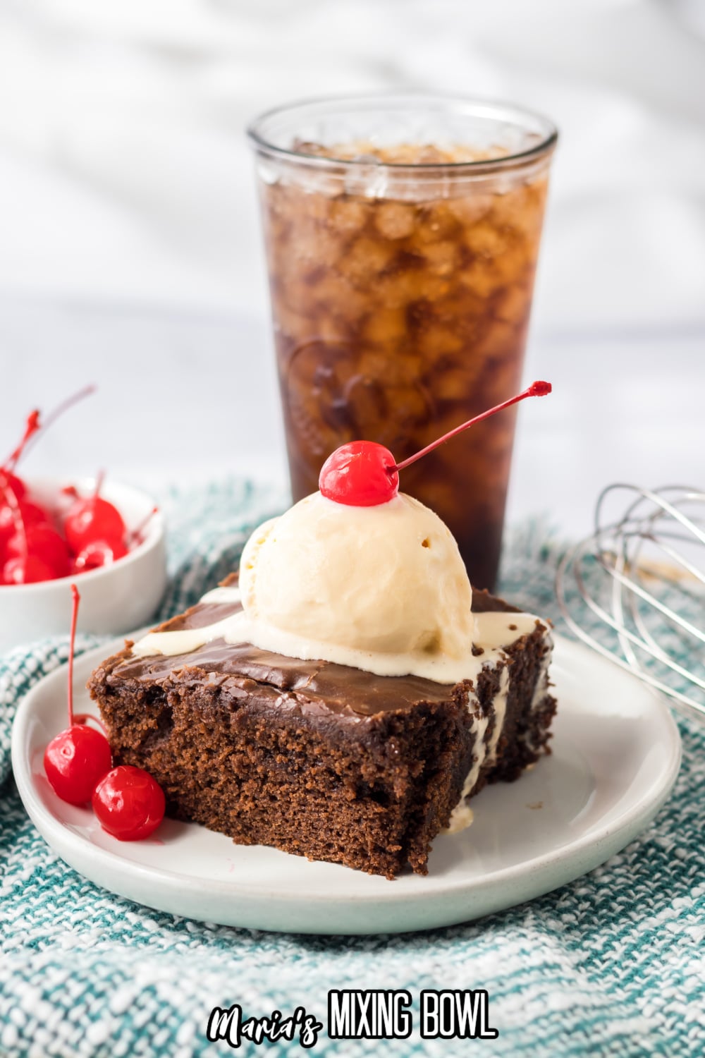 slice of double fudge coca cola cake on a small white plate topped with a scoop of ice cream