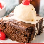 slice of double fudge coca cola cake on a small white plate topped with a scoop of ice cream