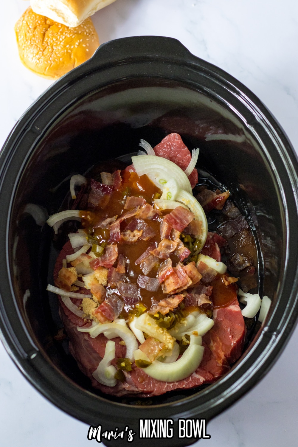 raw beef roast, onions, bacon, and seasonings in a slow cooker liner