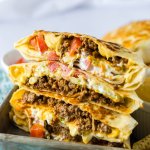 crunchwrap cut in half and stacked on top of each other on a metal tray.