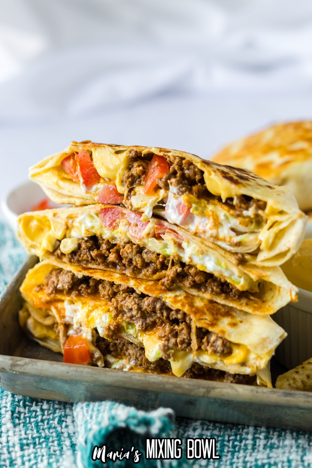 crunchwrap cut in half and stacked on top of each other on a metal tray.