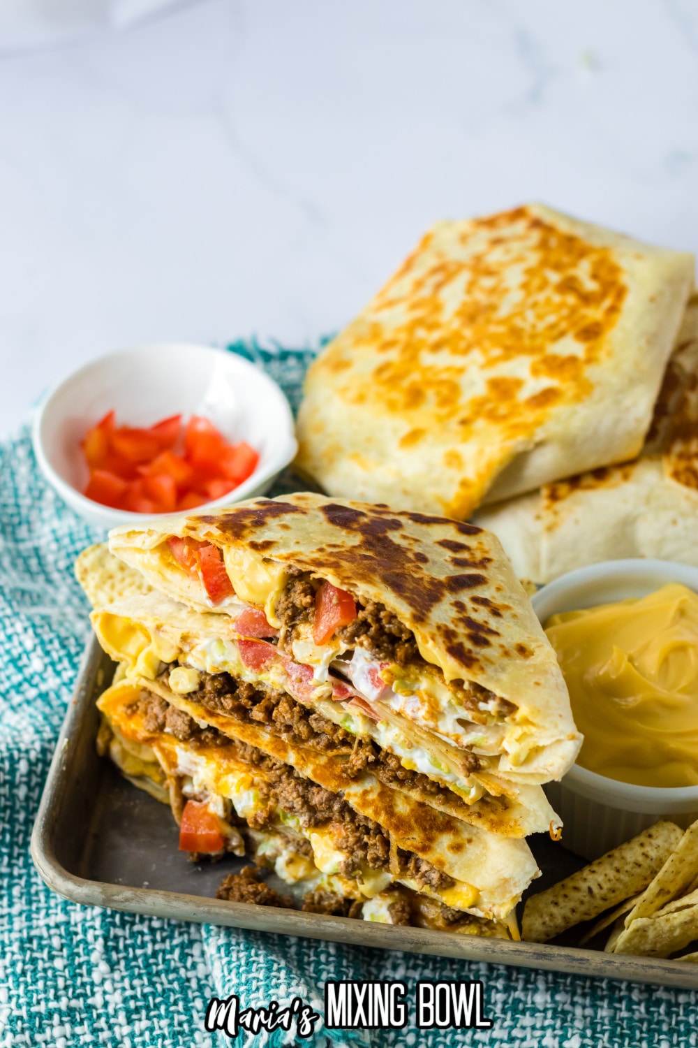 crunchwrap cut in half and stacked on top of each other on a metal tray.
