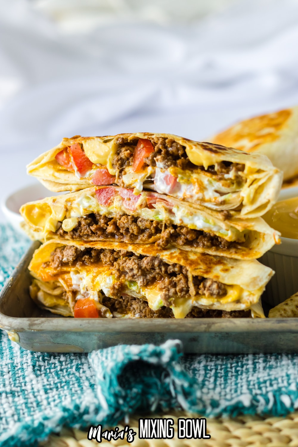 crunchwrap cut in half and stacked on top of each other on a metal tray.
