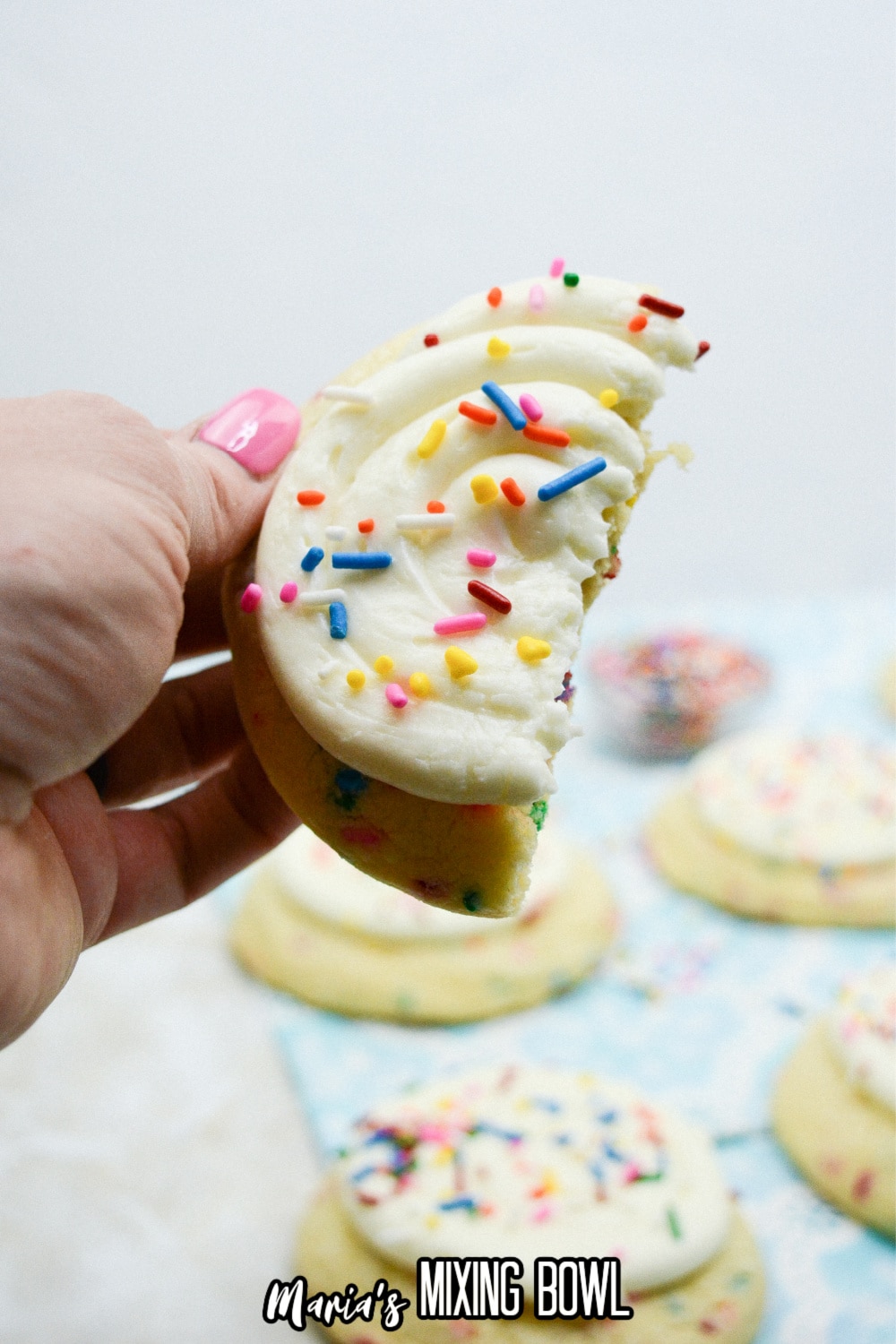 birthday cake cookie half held in the air in a woman's hand