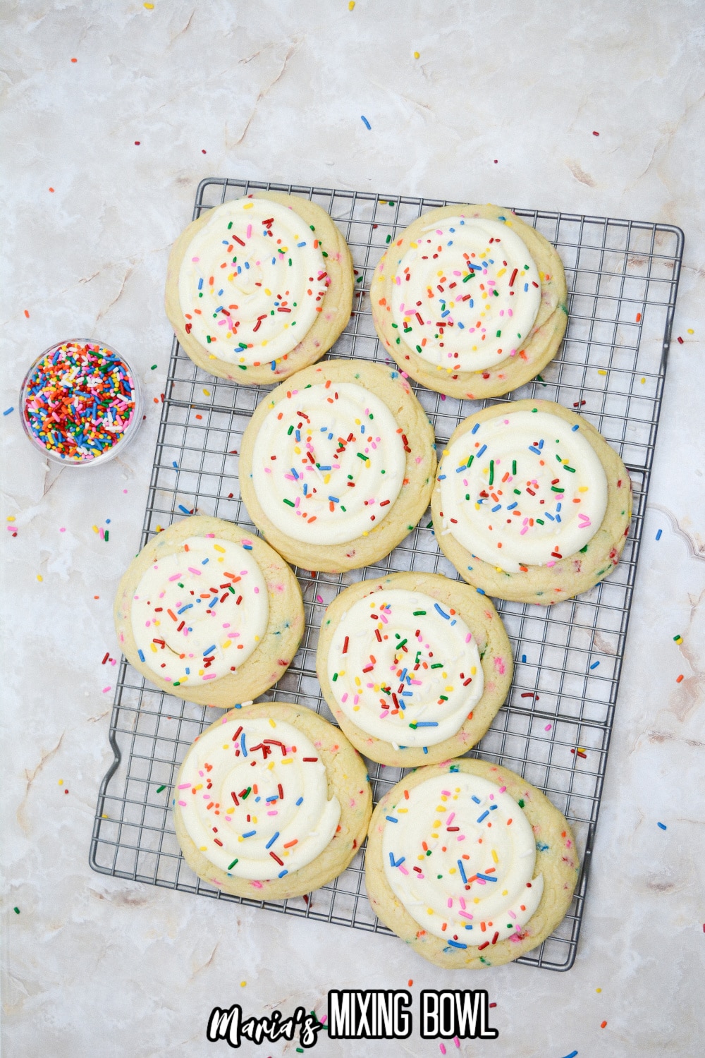 frosted sugar cookies being decorated on a wire cooling rack