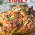 whole roasted chicken topped with fresh parsley in a glass baking dish