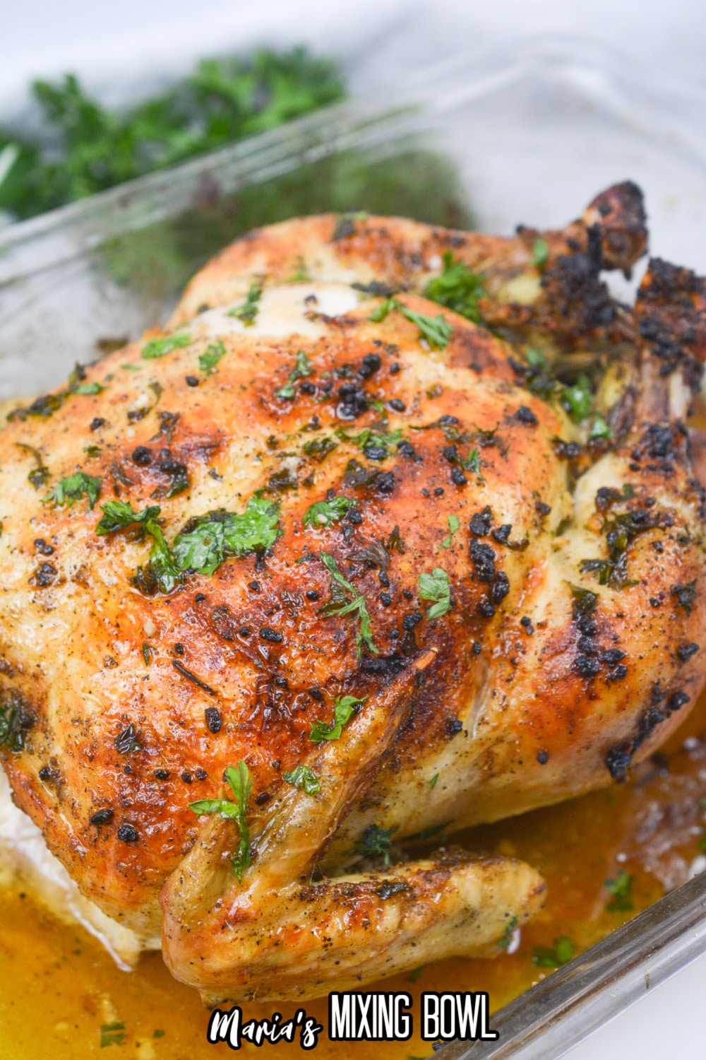 roasted chicken topped with fresh parsley in a glass baking dish