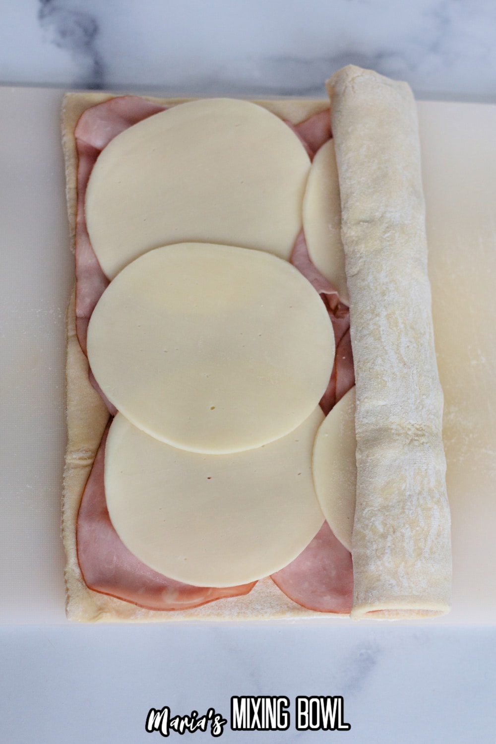 ham and cheese being rolled into puff pastry