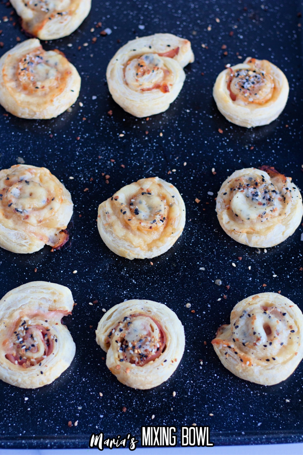 ham and cheese pinwheels cooling on dark baking sheet
