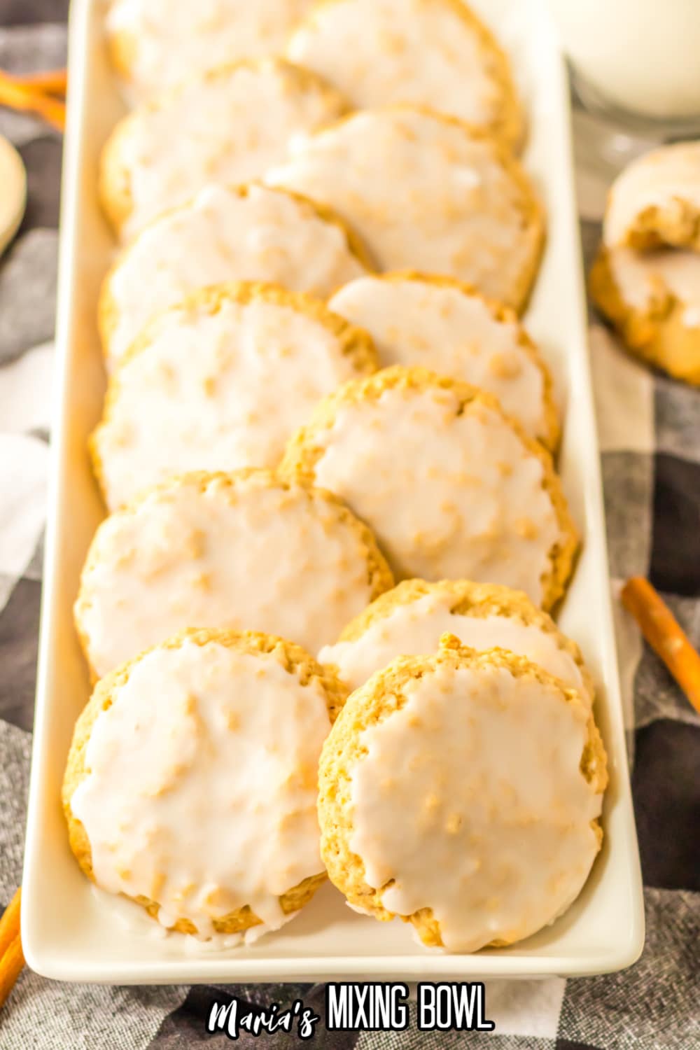 12 iced oatmeal cookies lined in two rows on a white rectangular platter.