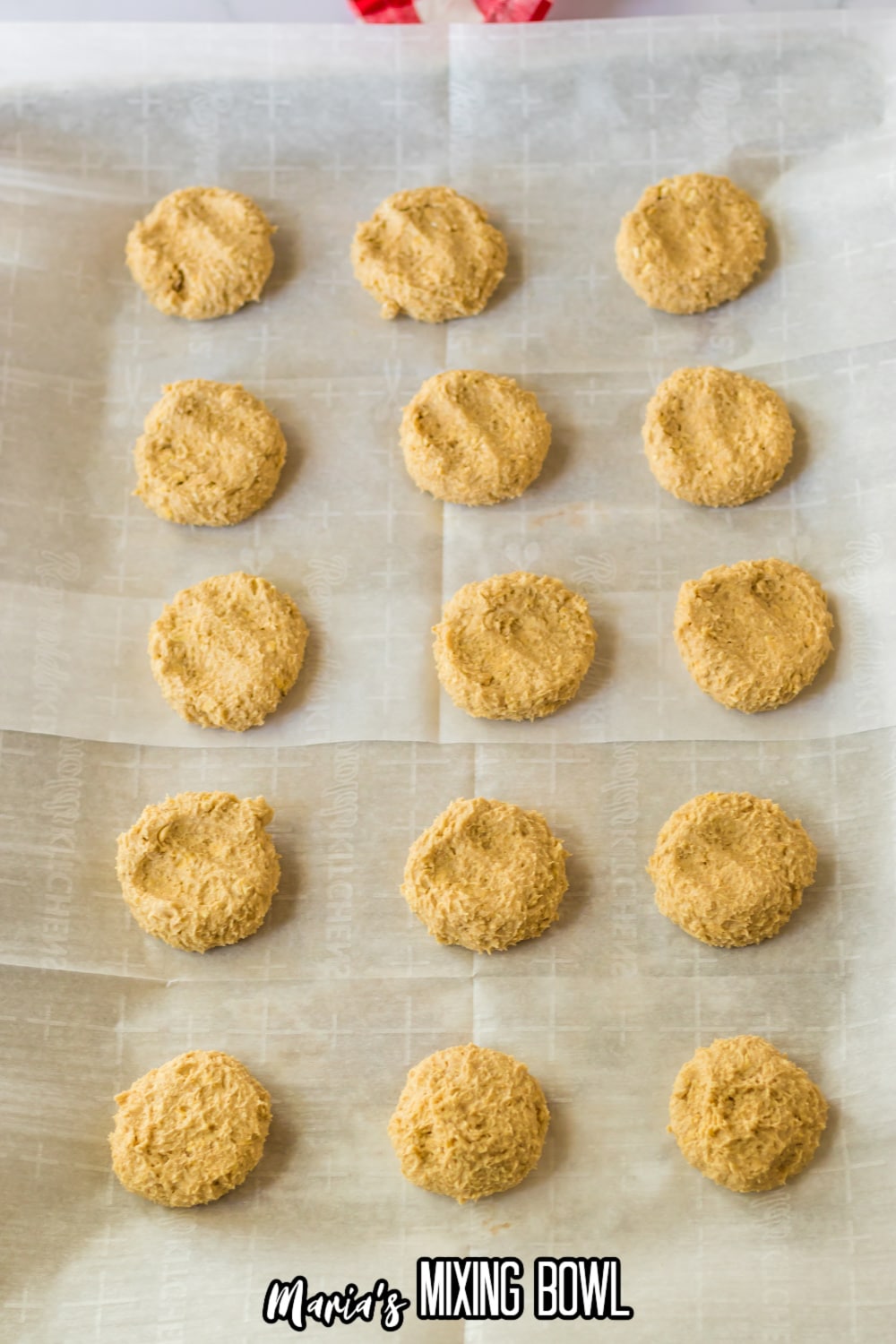 raw cookie dough pressed on a parchment lined baking sheet ready for the oven