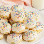 stack of italian ricotta cookies topped with pastel sprinkles on a white plate