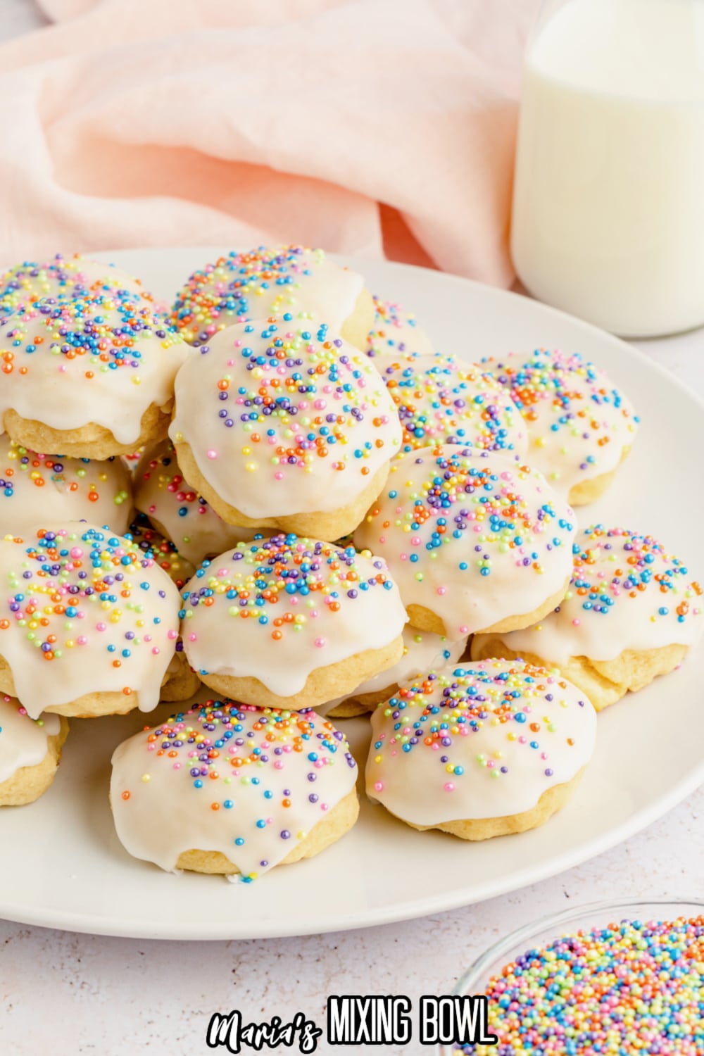 stack of italian ricotta cookies topped with pastel sprinkles on a white plate