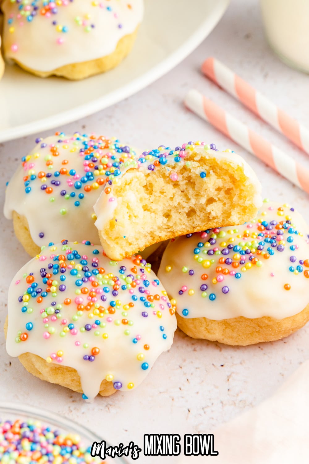 stack of four italian ricotta cookies on a white background with the top cookie bitten in half