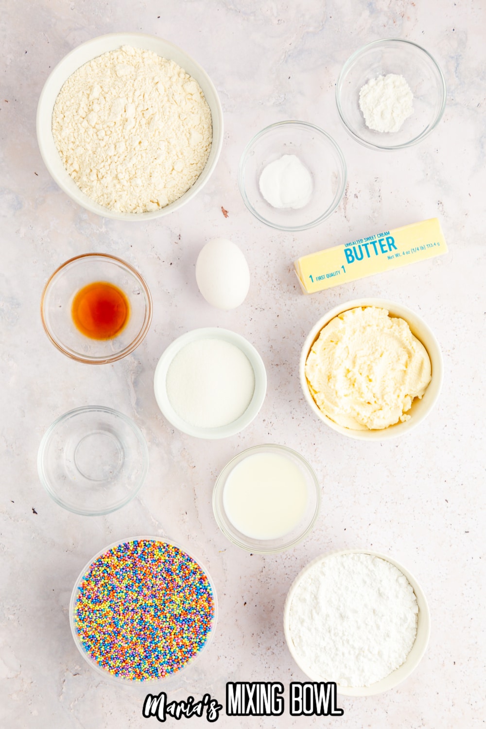 bowls of flour, baking soda, baking powder, salt, vanilla extract, butter, sugar, milk, powdered sugar and sprinkles