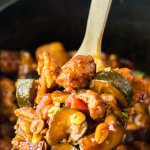 large wooden spoonful of kung pao chicken held above a slow cooker