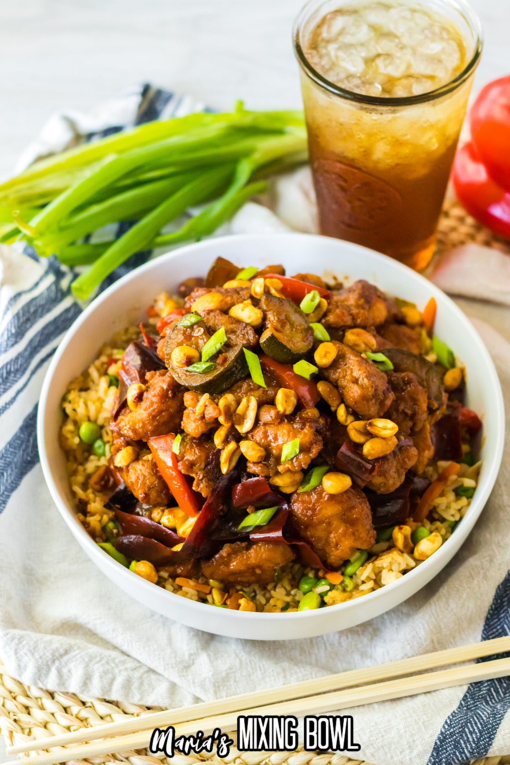 bowl filled with fried rice and kung pao chicken and topped with peanuts