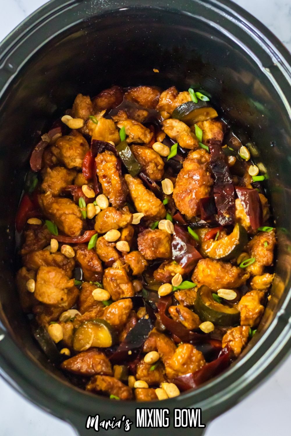 kung pao chicken topped with peanuts in the slow cooker