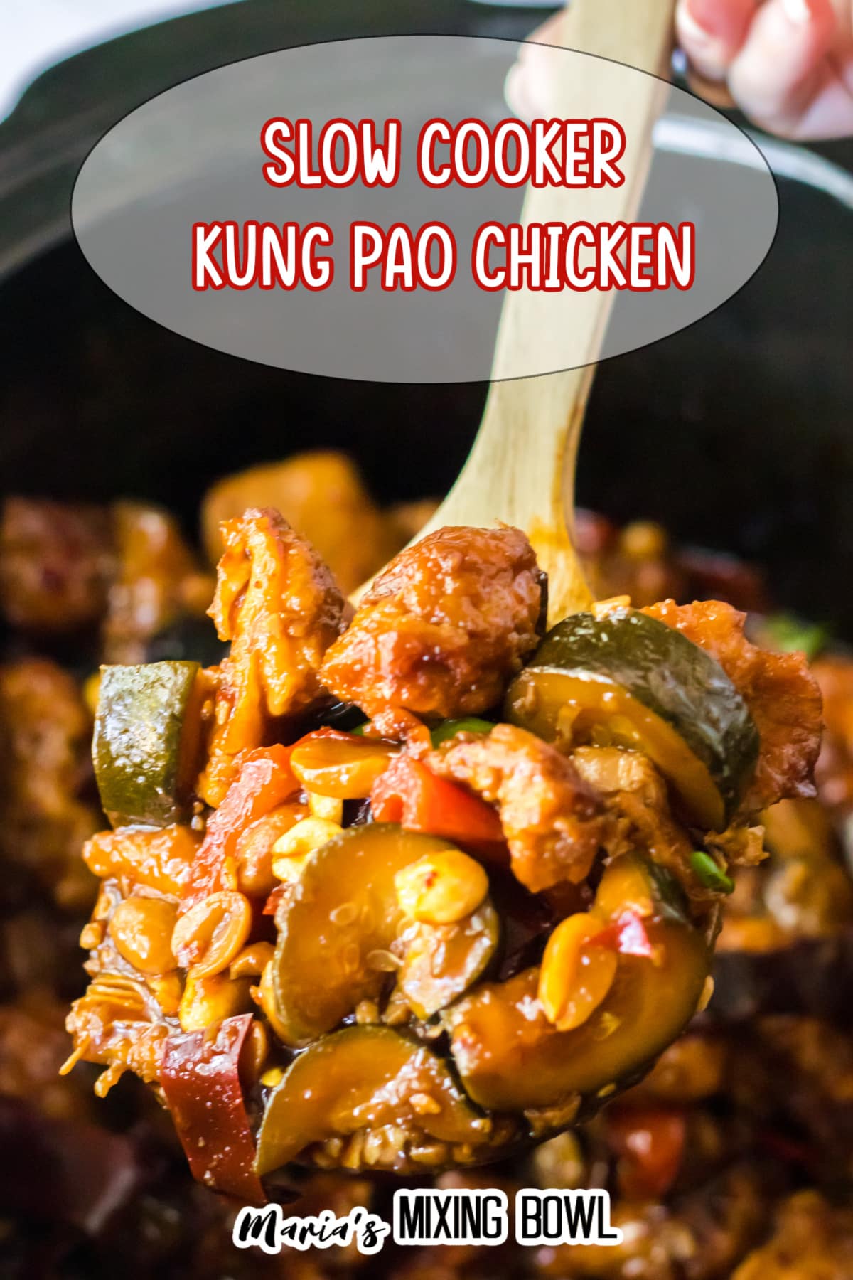 large wooden spoonful of kung pao chicken held above a slow cooker