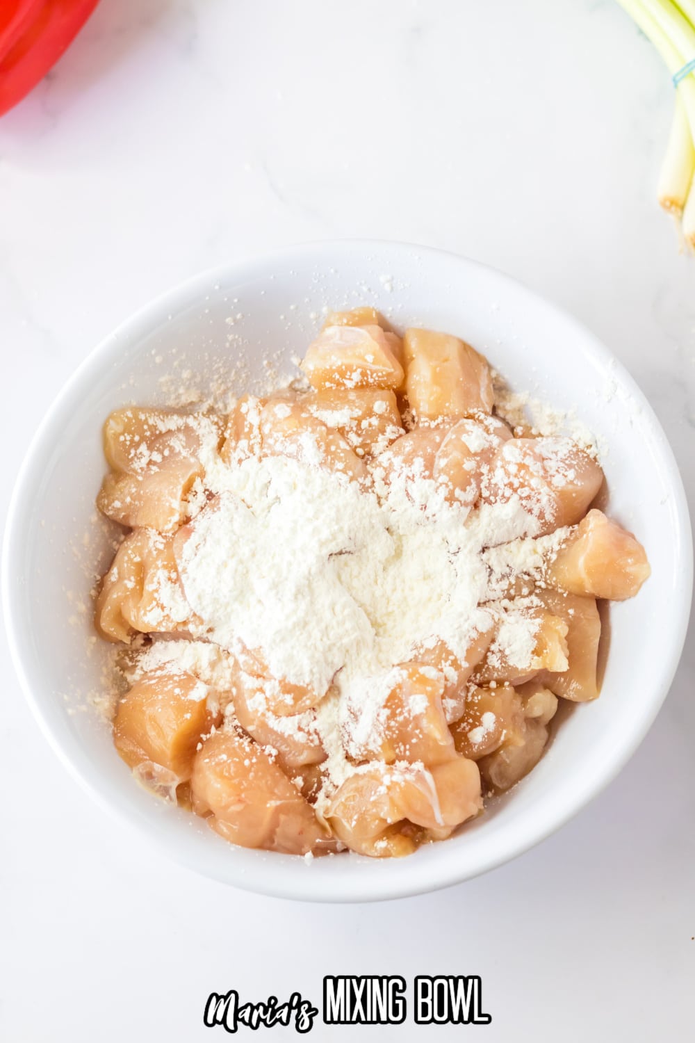 diced chicken breasts being coated in cornstarch in a bowl