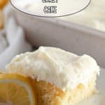 slice of lemon crazy cake frosting with cream cheese frosting on a white plate with lemon wedges