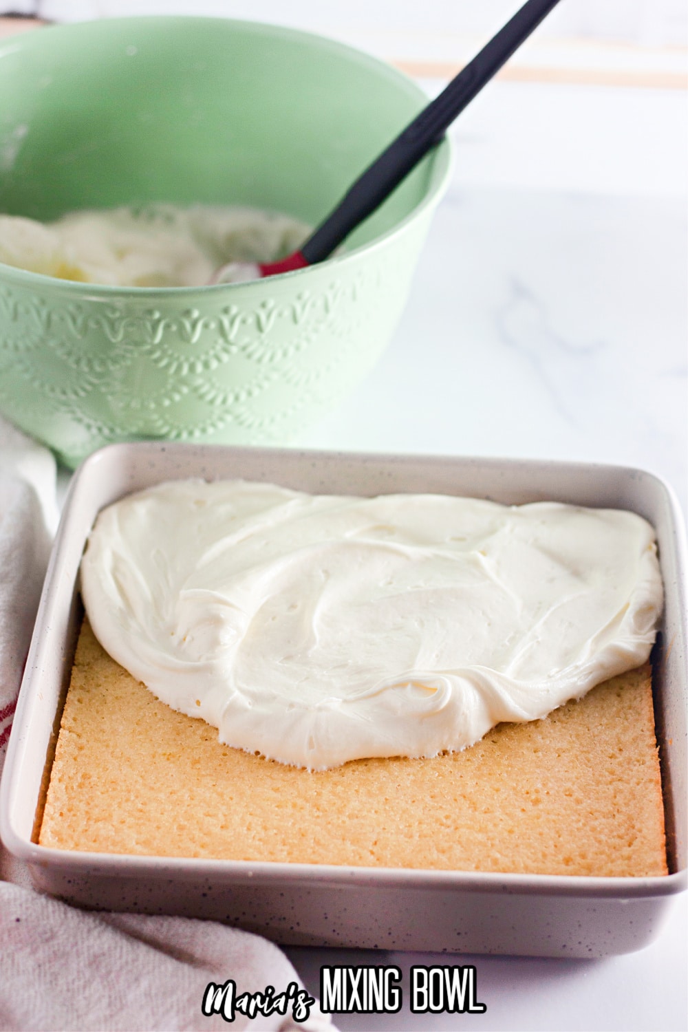 cream cheese frosting being spread on top of a cake in a rectangle pan