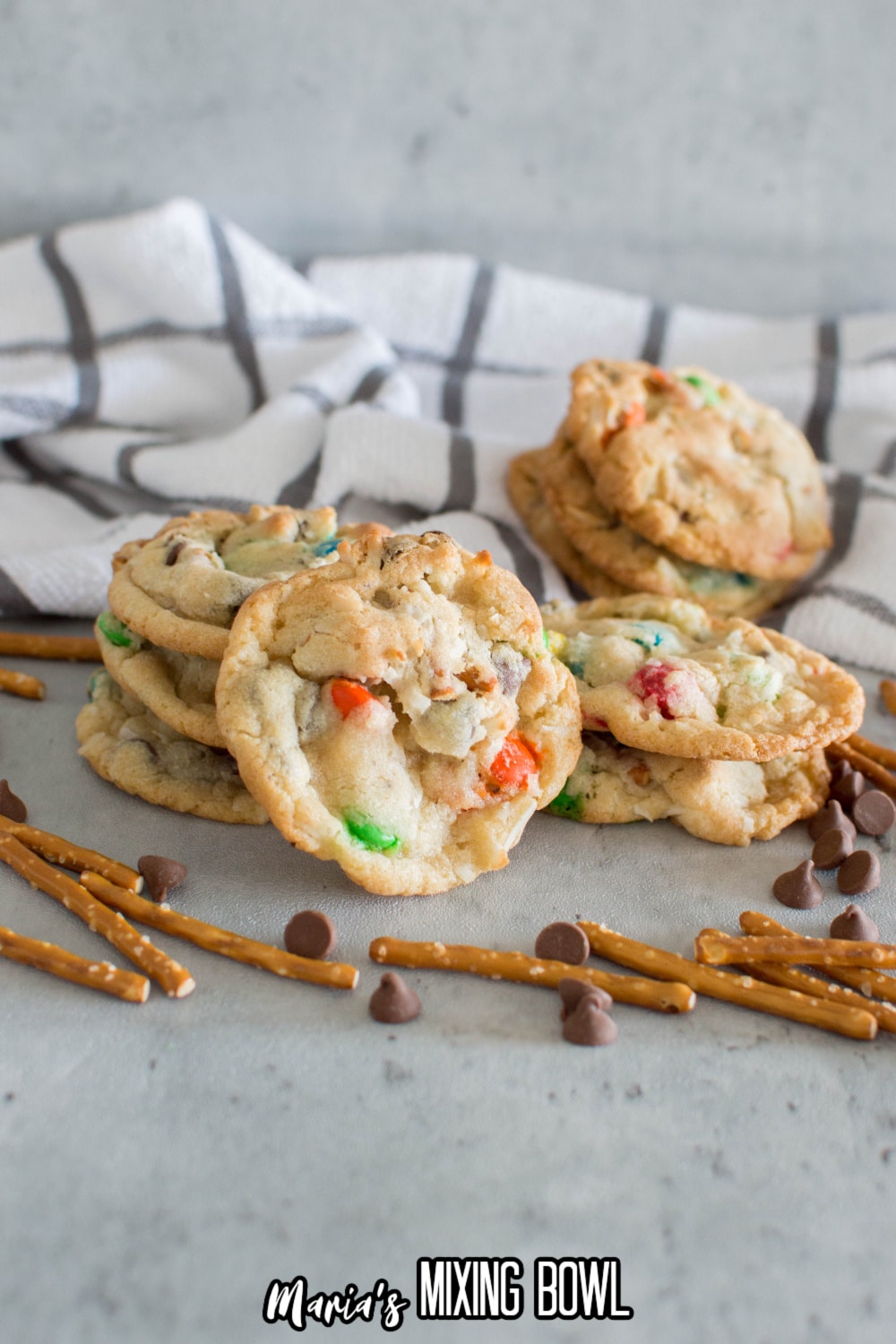 loaded pretzel cookies on a marble counter with pretzels and chocolate chips around it