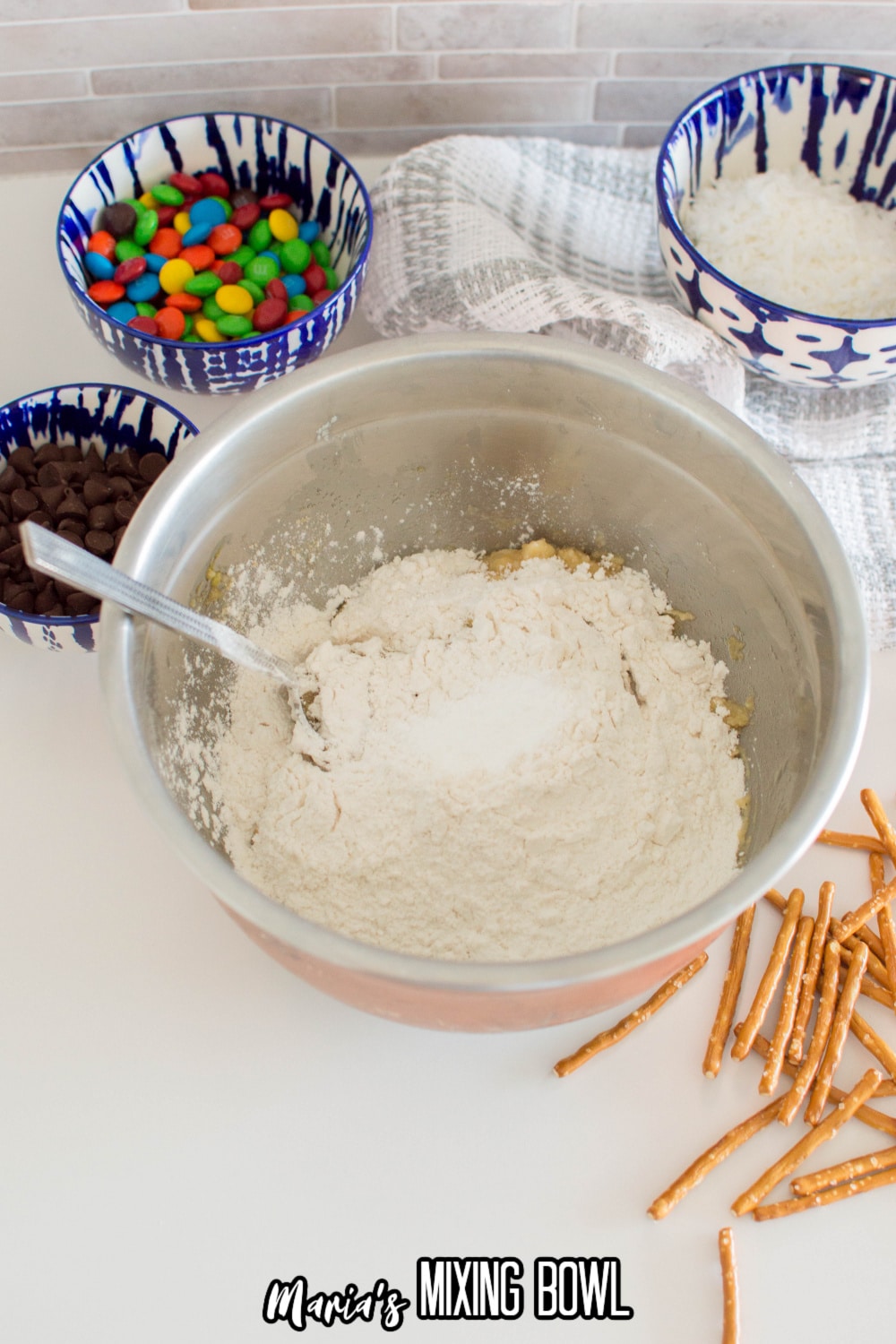 flour, salt, and baking powder being stirred into butter and sugar in a stainless steel mixing bowl