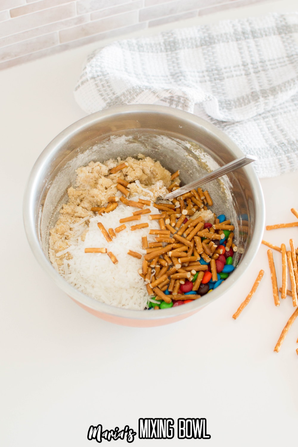 pretzels, coconut, and m&m's being folded into cookie dough