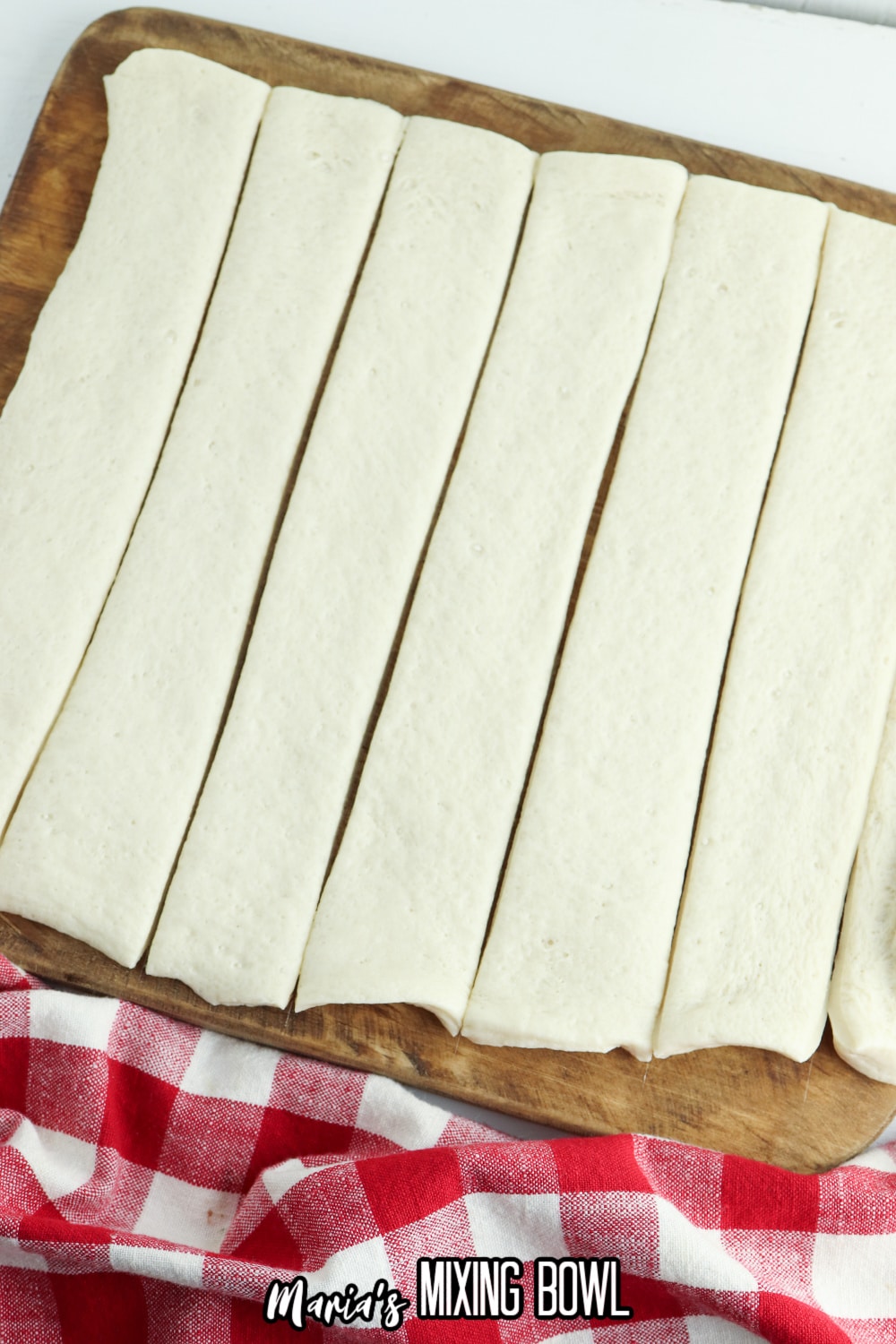 pizza dough cut into strips on a wooden cutting board