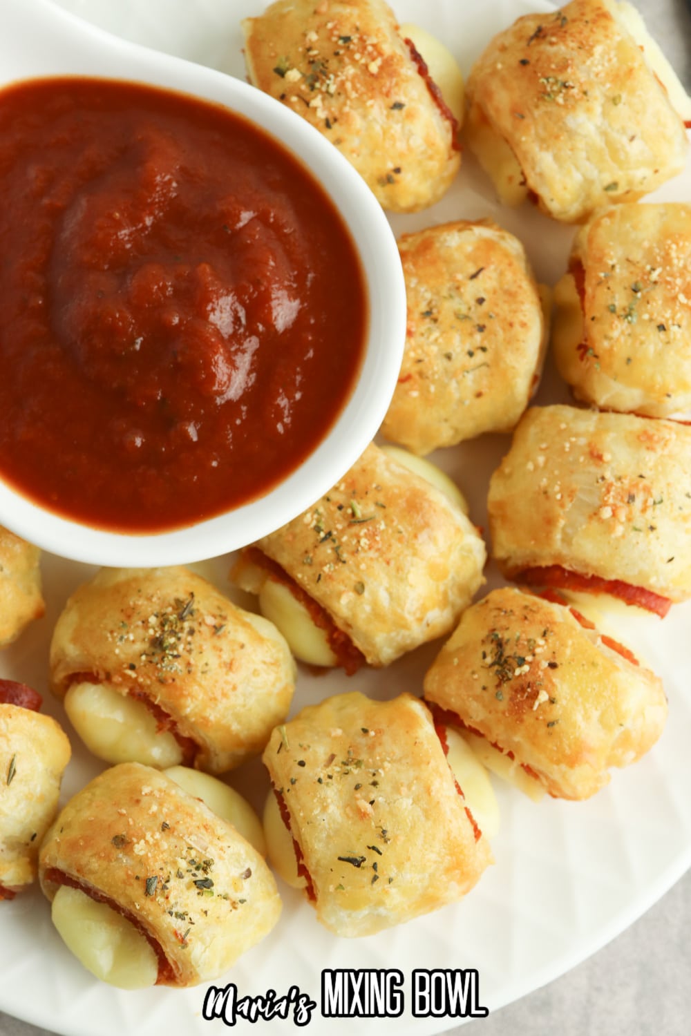 puff pastry pizza bites on a white plate with a bowl of marinara sauce