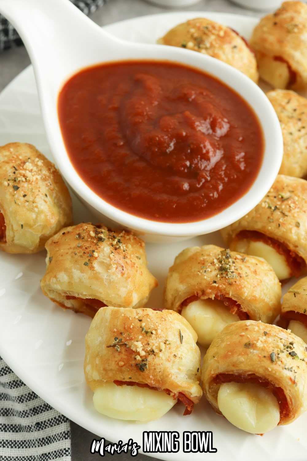 puff pastry pizza bites on a white plate with a bowl of marinara sauce