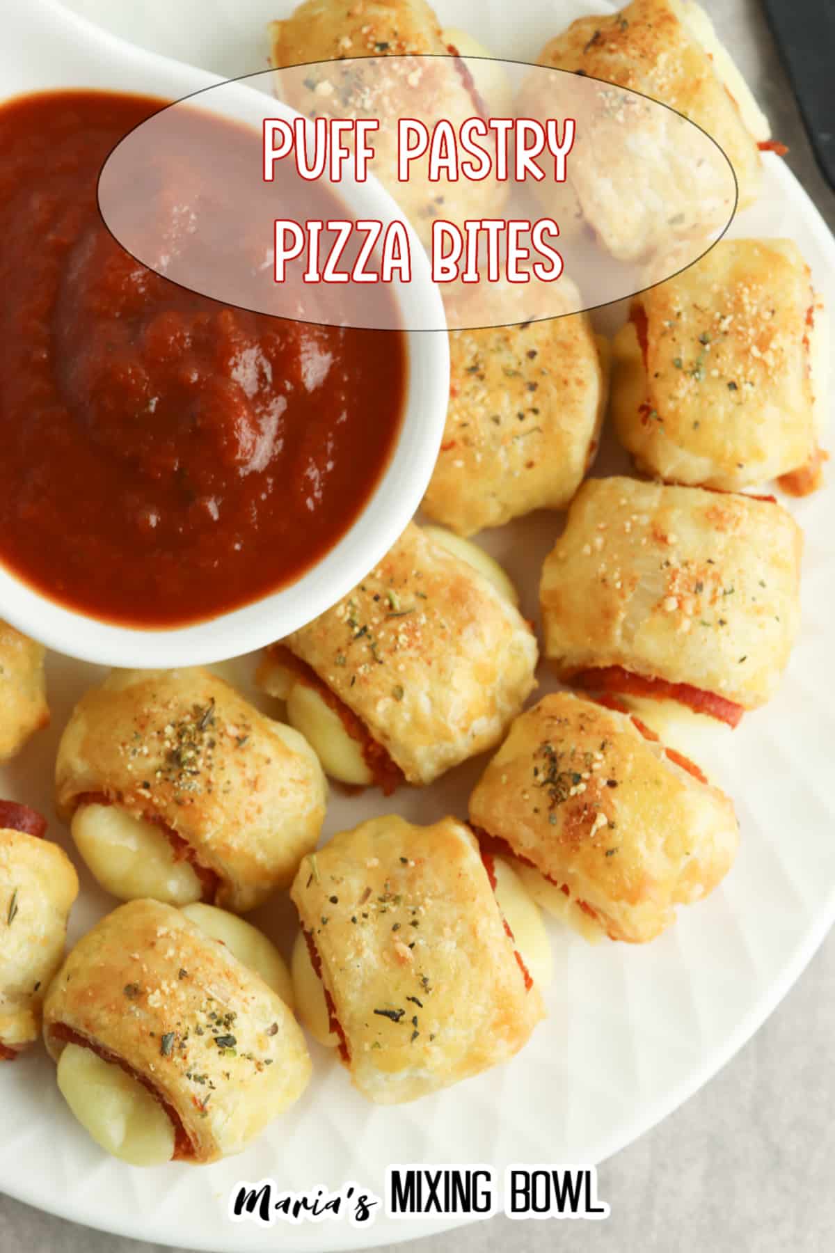 puff pastry pizza bites on a white plate with a bowl of marinara sauce