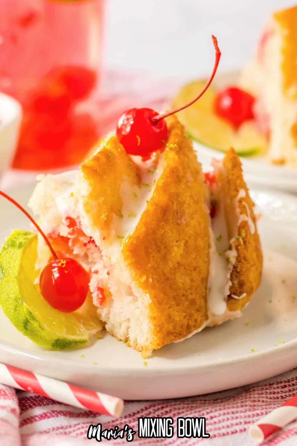 slice of Shirley temple cake topped with glaze and cherries on a white and gold plate