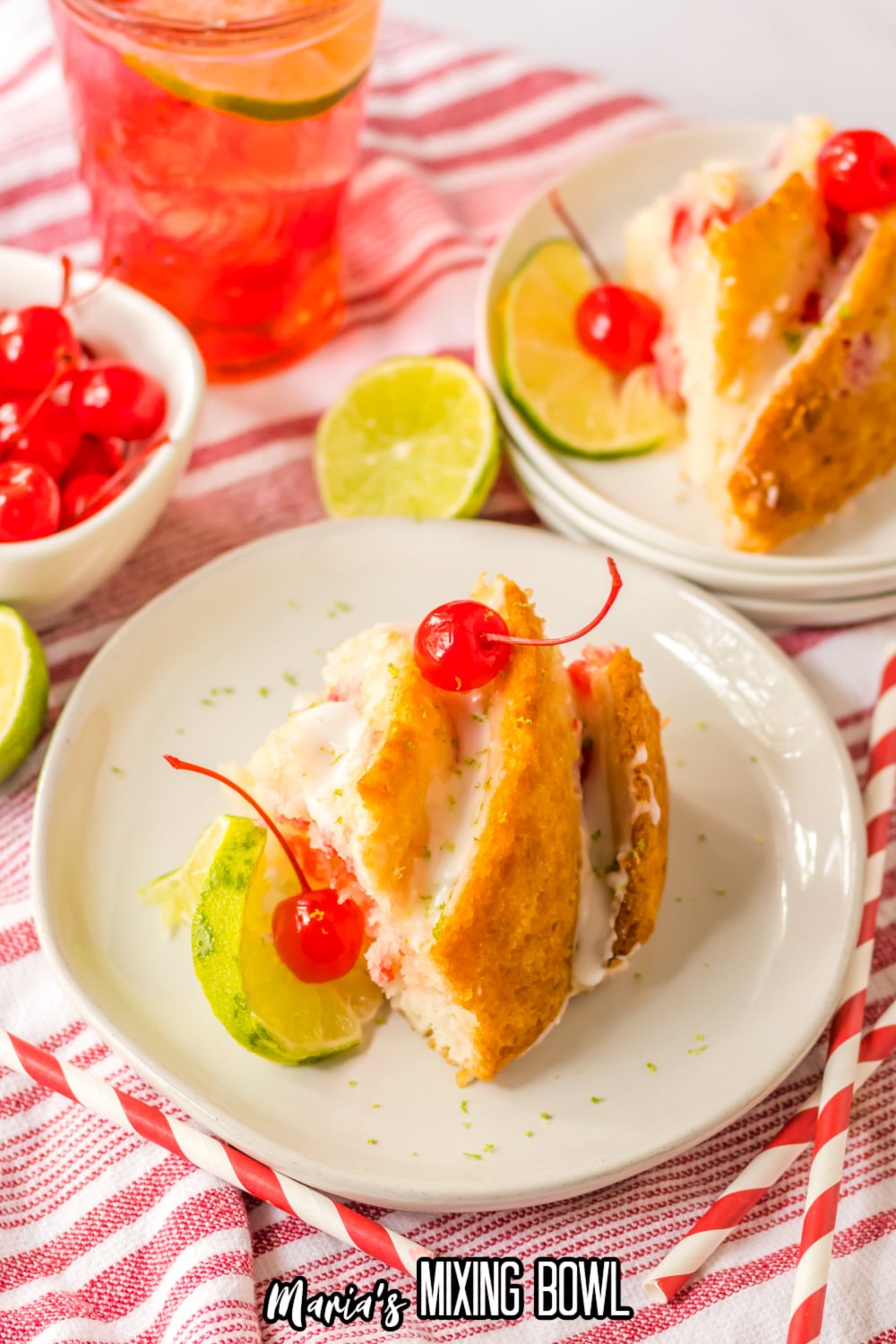 slice of Shirley temple cake topped with glaze and cherries on a white and gold plate