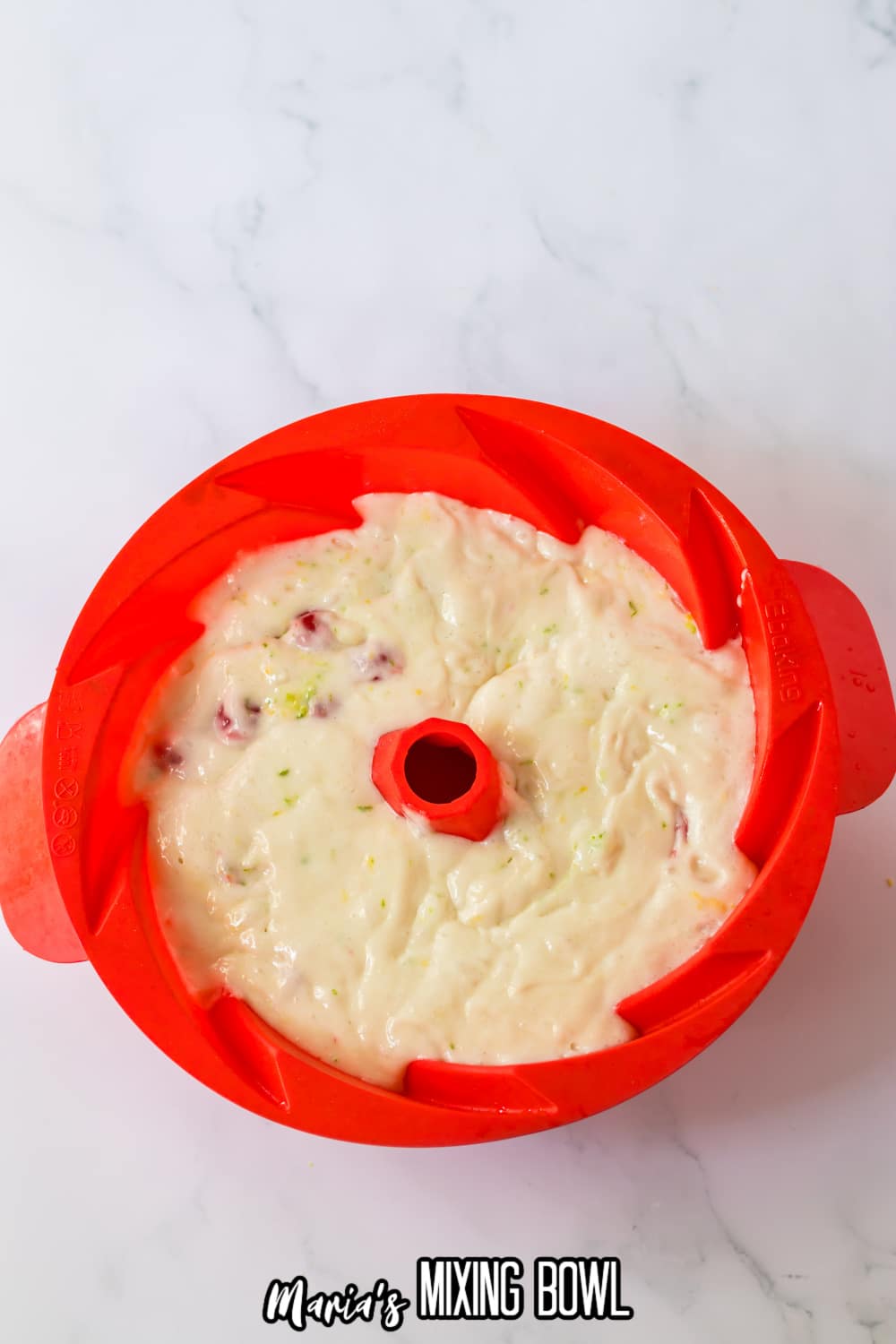 red silicone bundt cake pan filled with cake batter ready for the oven