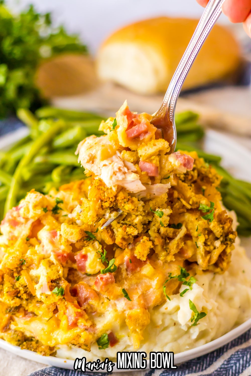 fork full of chicken cordon bleu on a plate with mashed potatoes and green beans